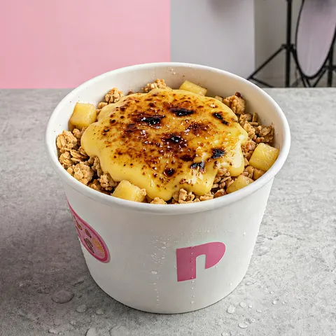 Pineapple crumble in a white peak cup: a torched custard top over granola and pineapple pieces.