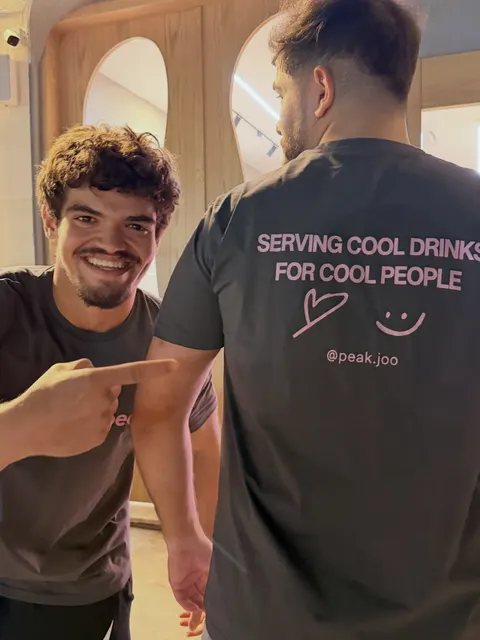 Hasan grinning and pointing at the print on a teammate's tee.